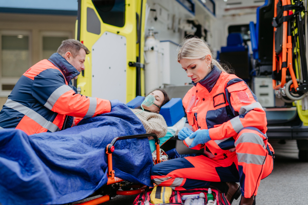 Rescuers taking care of a patient, preparing her for transport.