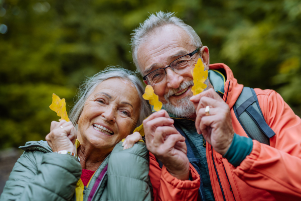 Portrait of happy senior couple with autumn leaves in a forest.