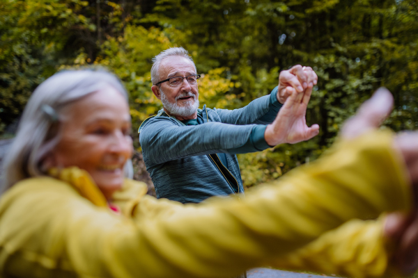 Senior couple doing stretching during hiking in autumn forest.