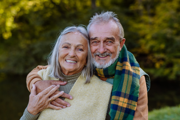 Portrait of happy senior couple walking in autumn nature.