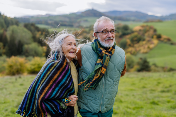 Happy senior couple walking in autumn nature.