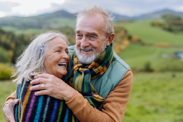 Portrait of happy senior couple walking in autumn nature.