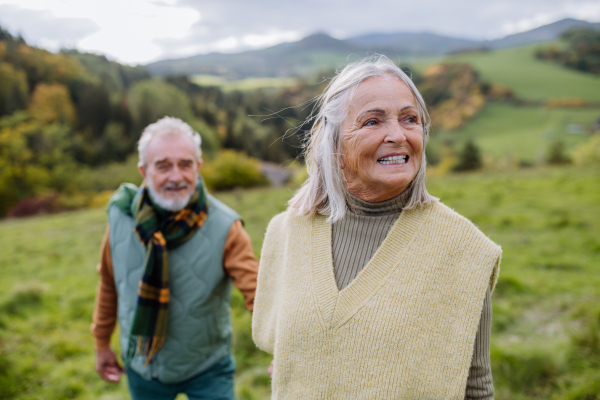 Portrait of happy senior couple walking in autumn nature.