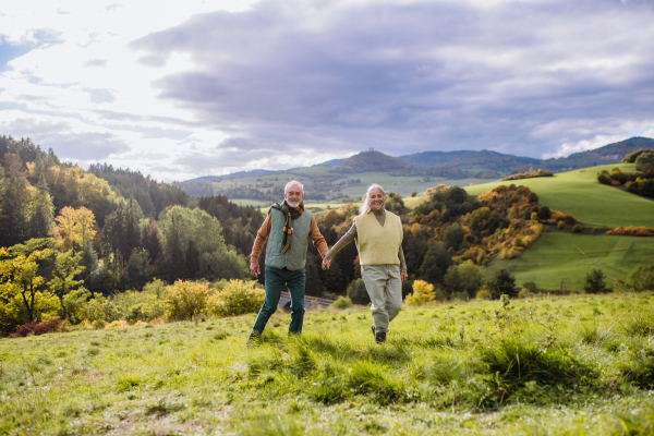 Happy senior couple walking in autumn nature.