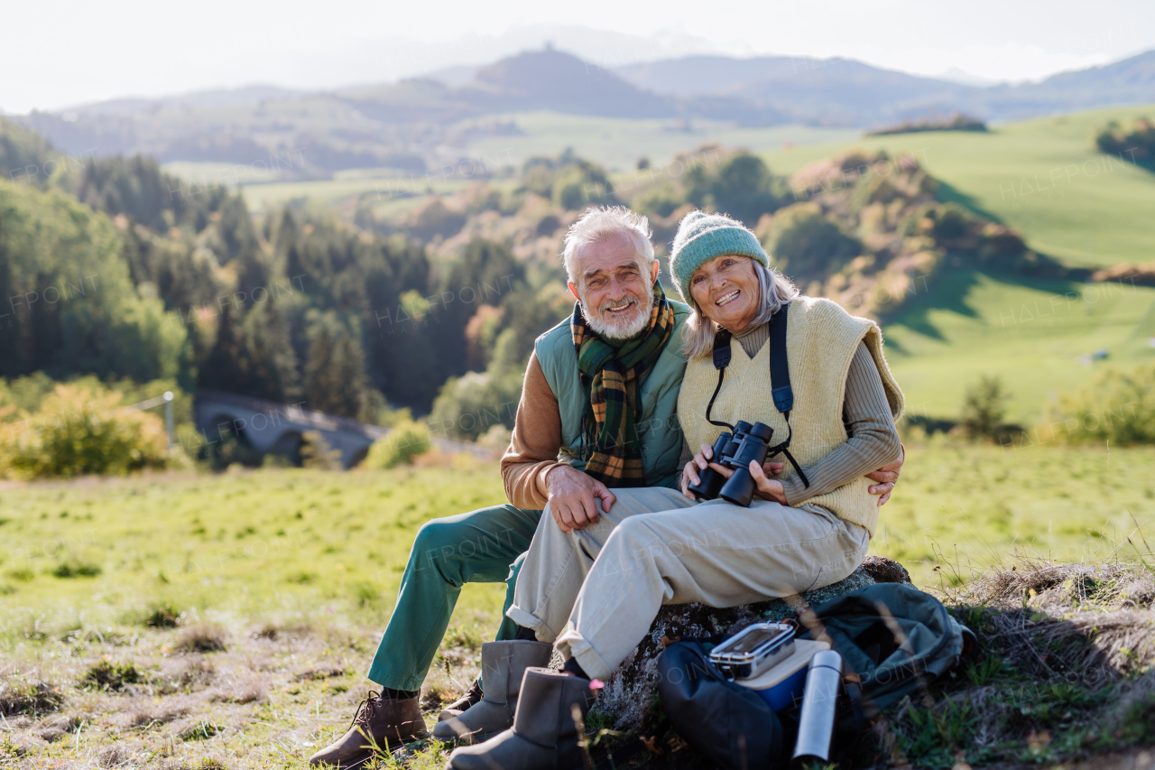 Senior couple having a break,sitting during hiking in autumn nature.