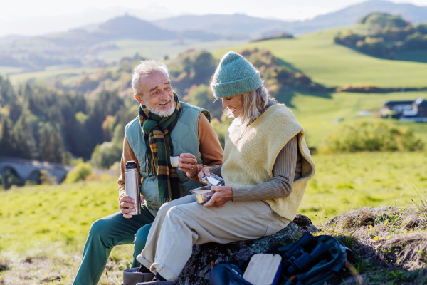 Senior couple having a break during hiking in autumn nature.