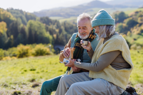 Senior couple having a break during hiking in autumn nature.