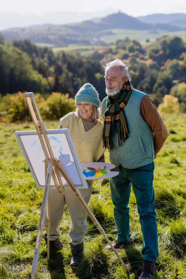 Senior couple painting surrounded autumn nature.