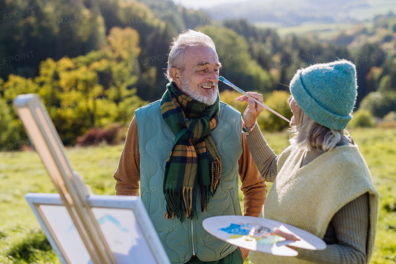 Senior couple painting surrounded autumn nature.