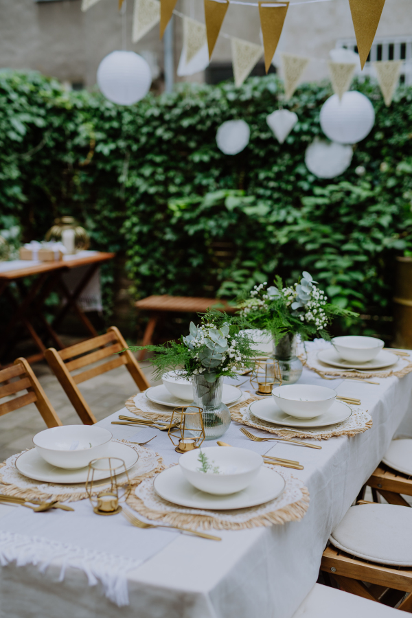 A festive wedding table setting with flowers at small reception in backyard in summer.