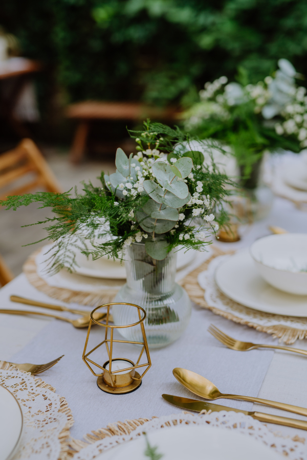 A festive wedding table setting with flowers at small reception in backyard in summer.