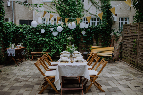 A festive wedding table setting with flowers at small reception in backyard in summer.