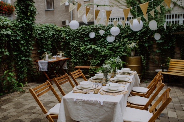 A festive wedding table setting with flowers at small reception in backyard in summer.