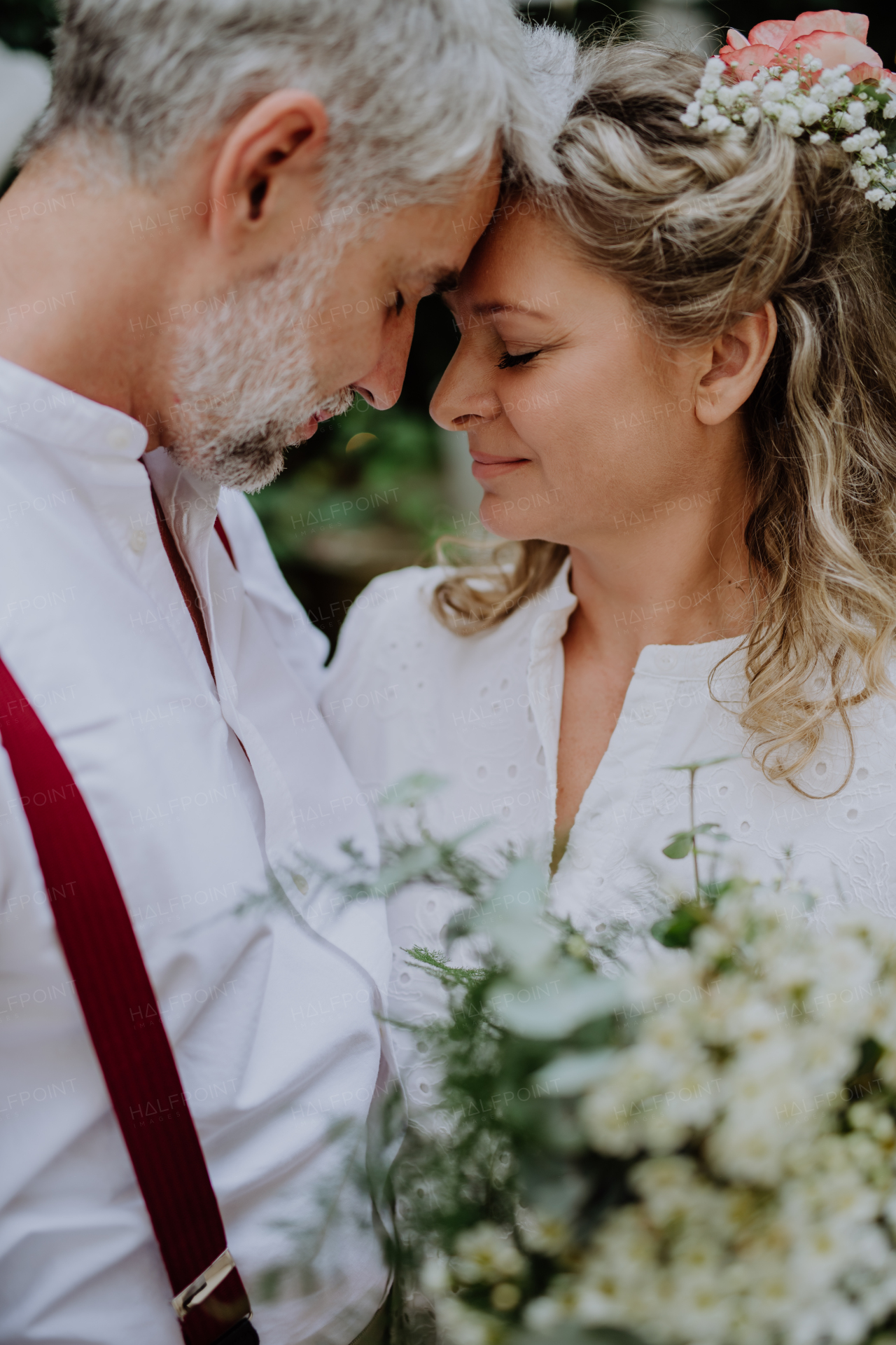 A mature bride and groom having a romantic moment at wedding reception outside in the backyard.