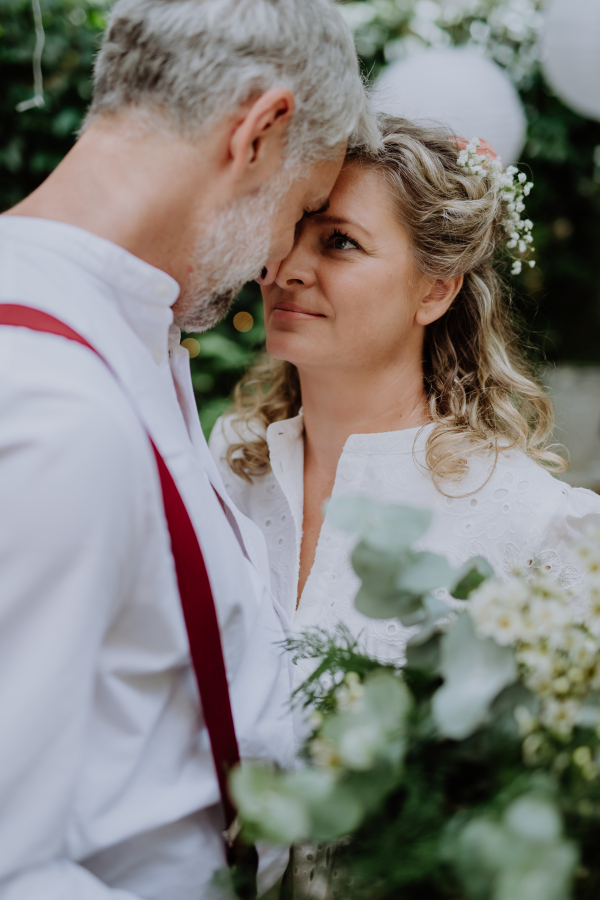 A mature bride and groom having a romantic moment at wedding reception outside in the backyard.