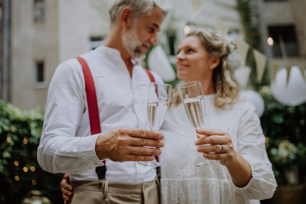 A mature bride and groom toasting at wedding reception outside in the backyard.