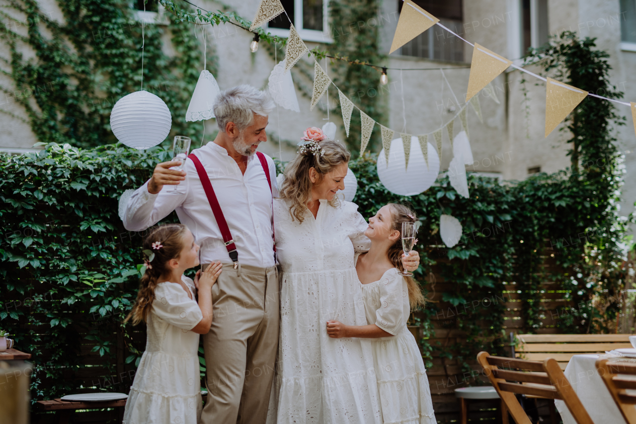 A mature bride and groom receiving congratulations after at wedding reception outside in the backyard.