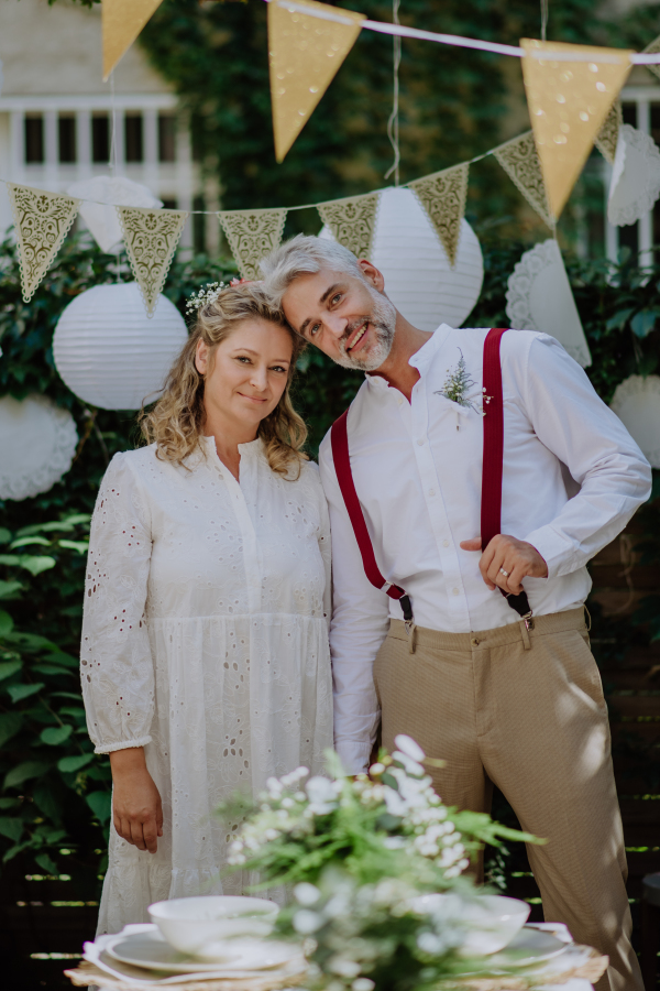 A mature bride and groom having a romantic moment at wedding reception outside in the backyard.