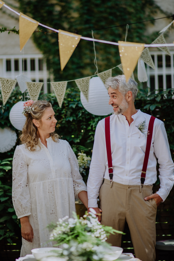 A mature bride and groom having a romantic moment at wedding reception outside in the backyard.