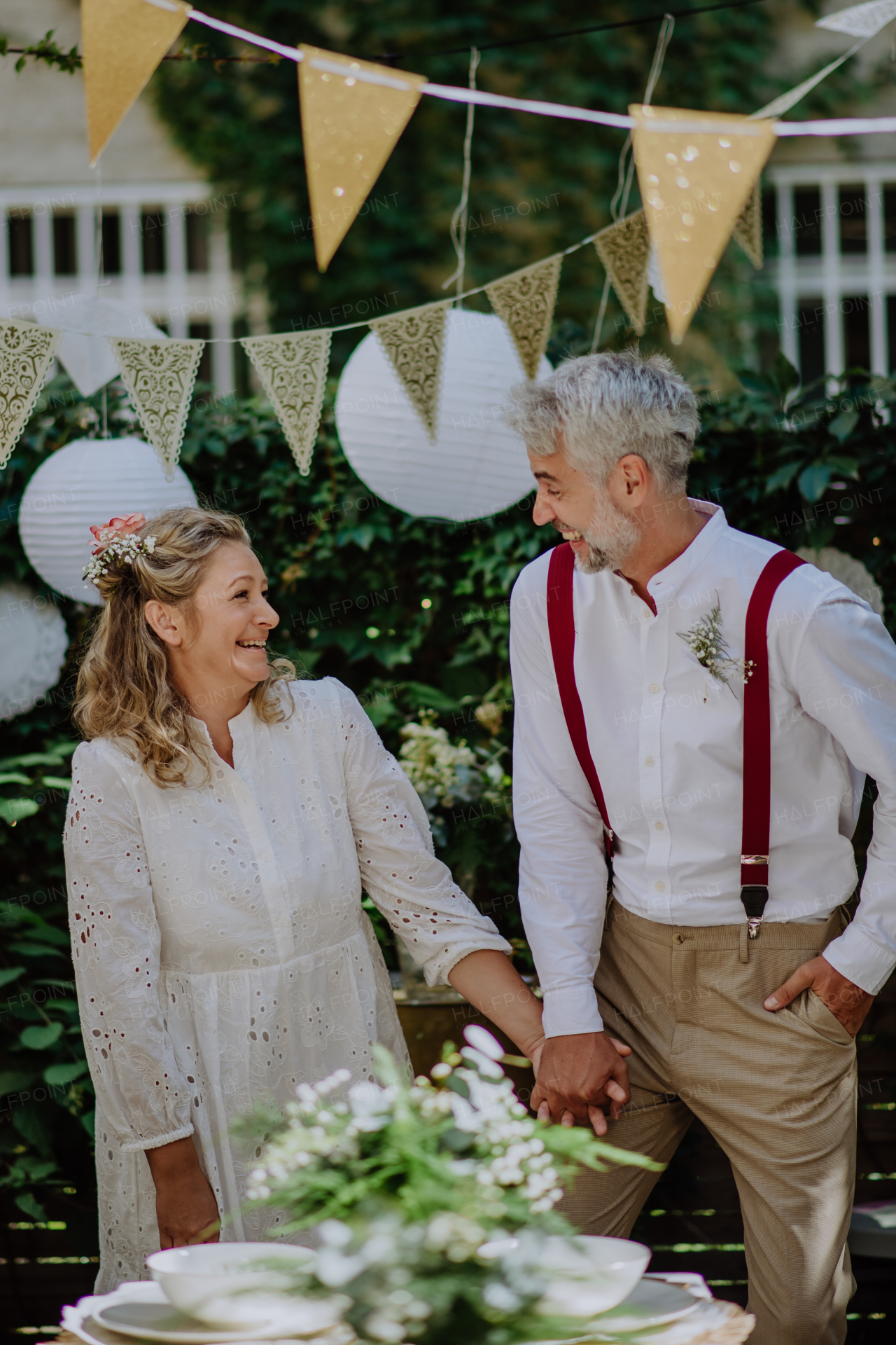 A mature bride and groom having a romantic moment at wedding reception outside in the backyard.