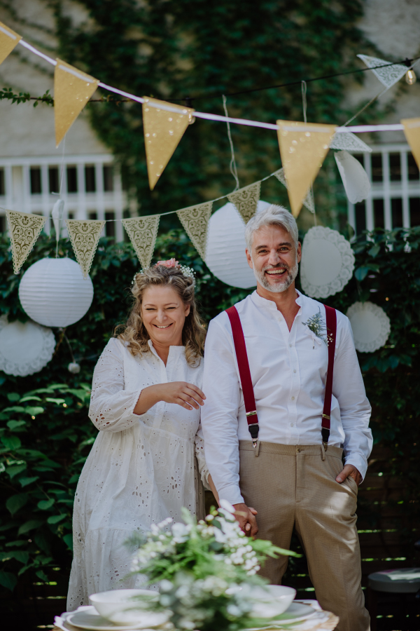 A mature bride and groom having a romantic moment at wedding reception outside in the backyard.