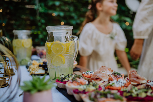 A close-up of dessert buffet at small wedding reception outside in the backyard, little girls in background.