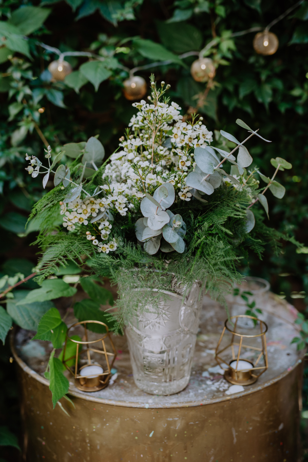 A glass vase with flowers with decorations on Boho wedding celebration.