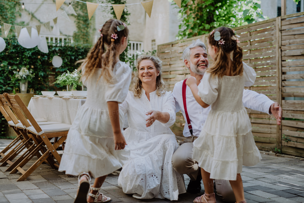 A mature bride and groom receiving congratulations after at wedding reception outside in the backyard.