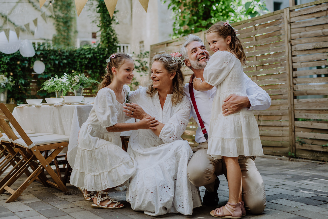 A mature bride and groom receiving congratulations after at wedding reception outside in the backyard.