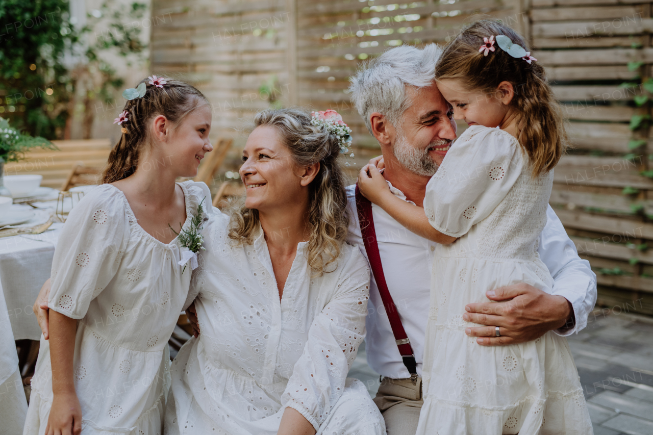 A mature bride and groom receiving congratulations after at wedding reception outside in the backyard.