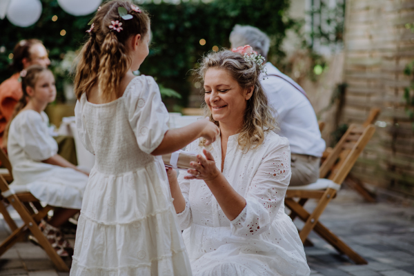 Little girl giving a wedding gift to mature bride at wedding backyard party.