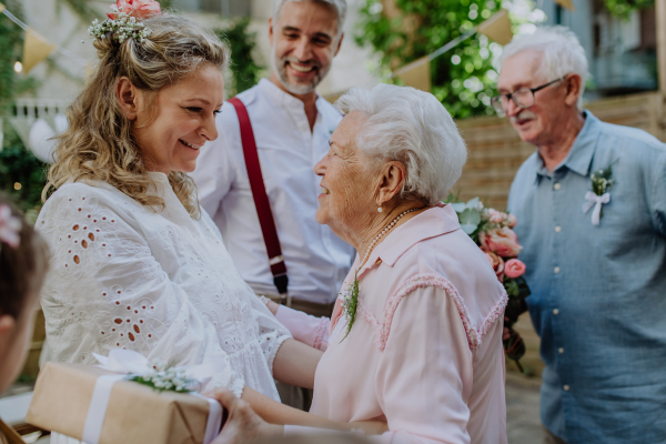 A mature bride and groom receiving congratulations at wedding reception outside in the backyard.