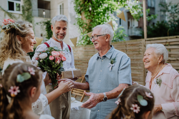 A mature bride receiving congratulations at wedding reception outside in the backyard.