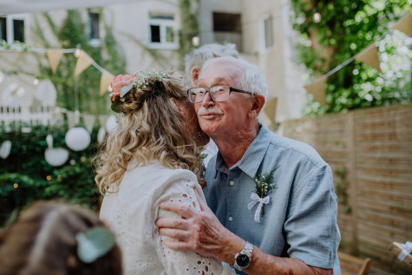 A mature bride receiving congratulations at wedding reception outside in the backyard.