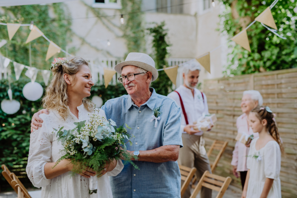 Mature bride with her dad at wedding garden ceremony.