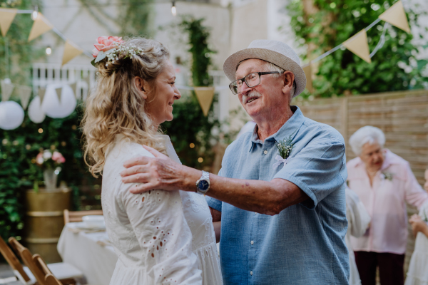 A mature bride receiving congratulations at wedding reception outside in the backyard.