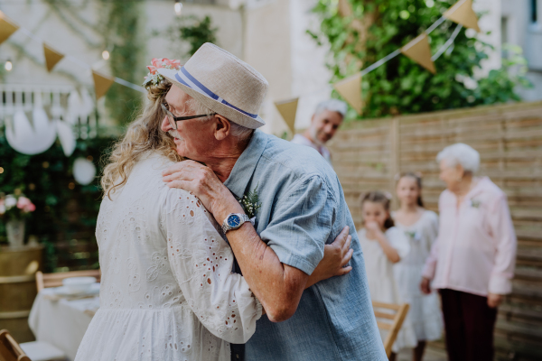 A mature bride receiving congratulations at wedding reception outside in the backyard.