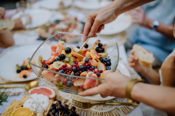 Wedding hosts serving fruit salad at outdoor garden party.