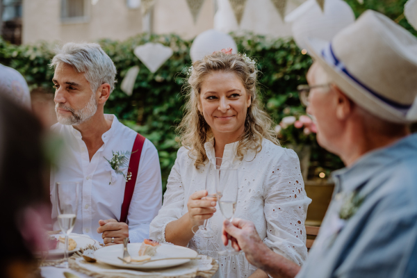 A mature bride and groom toasting with guests at wedding reception outside in the backyard.