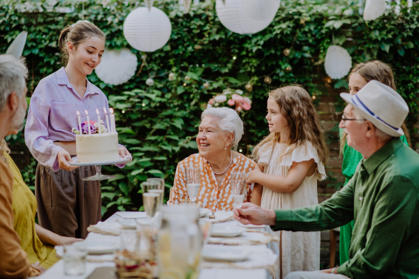 A multi-generation family on outdoor summer garden party, celebrating birthday