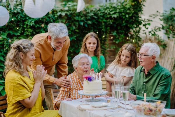 A multi-generation family on outdoor summer garden party, celebrating birthday