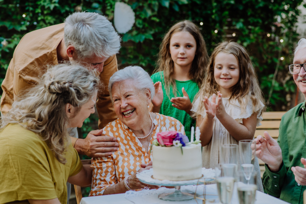 A multi-generation family on outdoor summer garden party, celebrating birthday