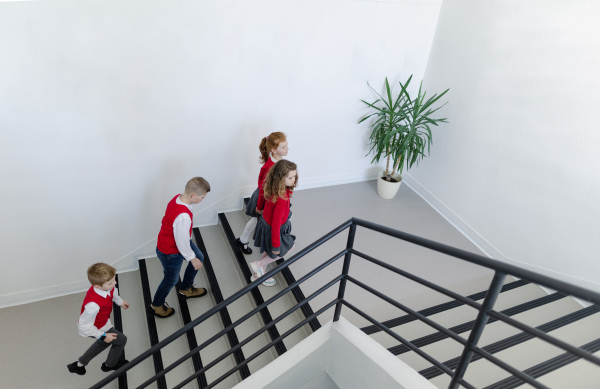 High angle view of schoolchildren in uniforms walking in a school staircase.