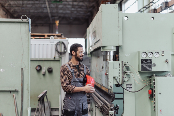 A heavy industry worker with safety headphones and hard hat in industrial factory