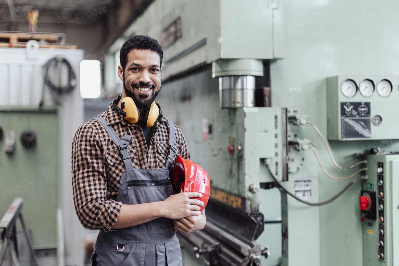 A heavy industry worker with safety headphones and hard hat in industrial factory