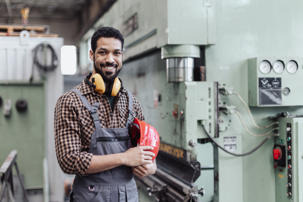 A heavy industry worker with safety headphones and hard hat in industrial factory