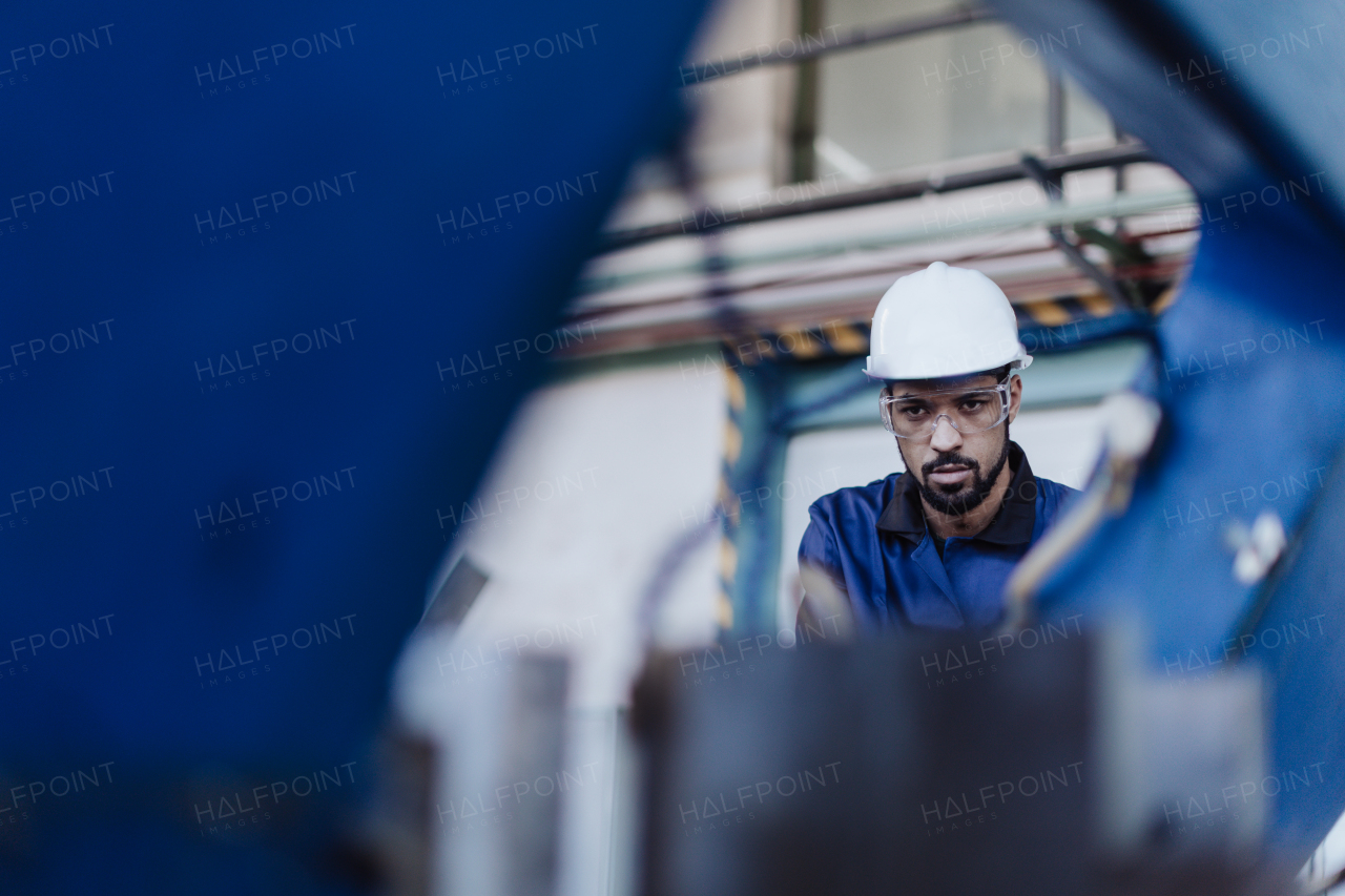 A factory male worker in plant production drilling at metal machine in industrial factory.