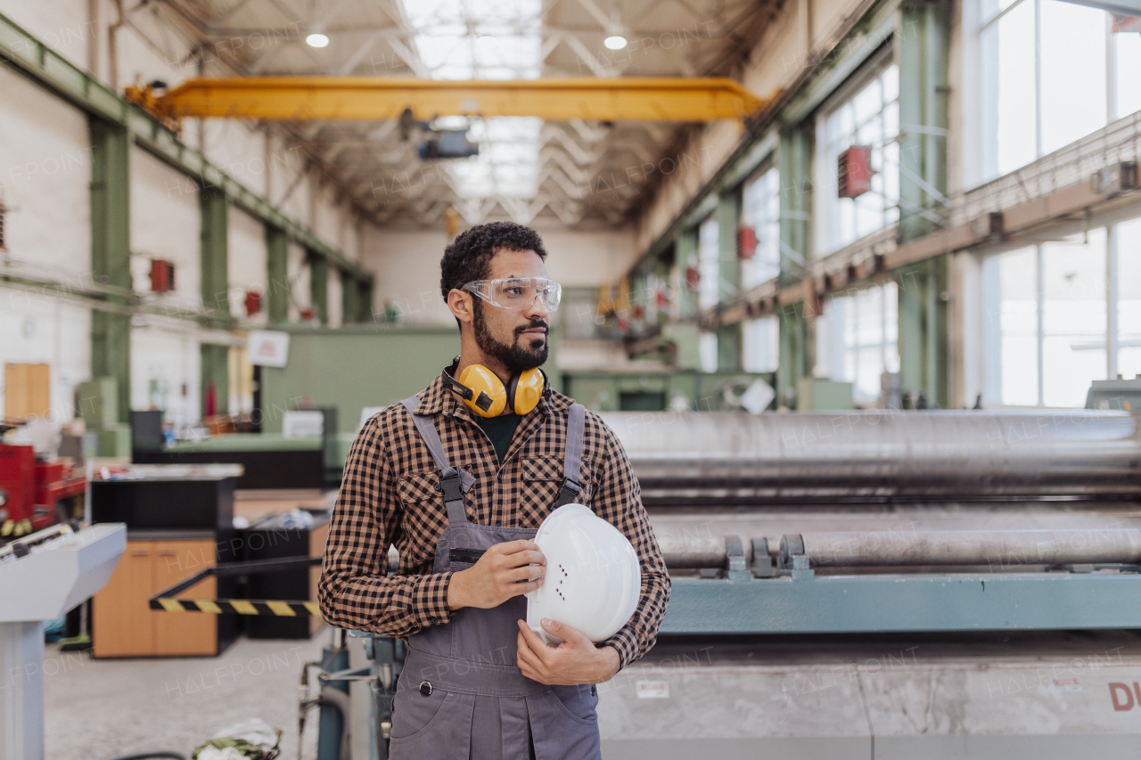 A heavy industry worker with safety headphones and hard hat in industrial factory