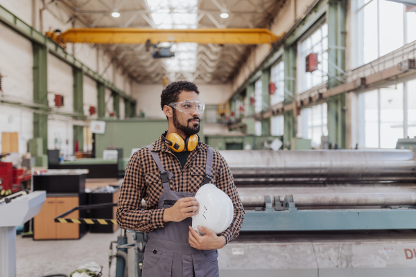 A heavy industry worker with safety headphones and hard hat in industrial factory