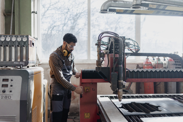 A portrait of heavy industry worker with safety headphones and in industrial factory